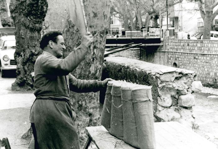 Jean Ros fabriquant un bât : La paille remplissant les coussinets est tassée au moyen d'une planche.